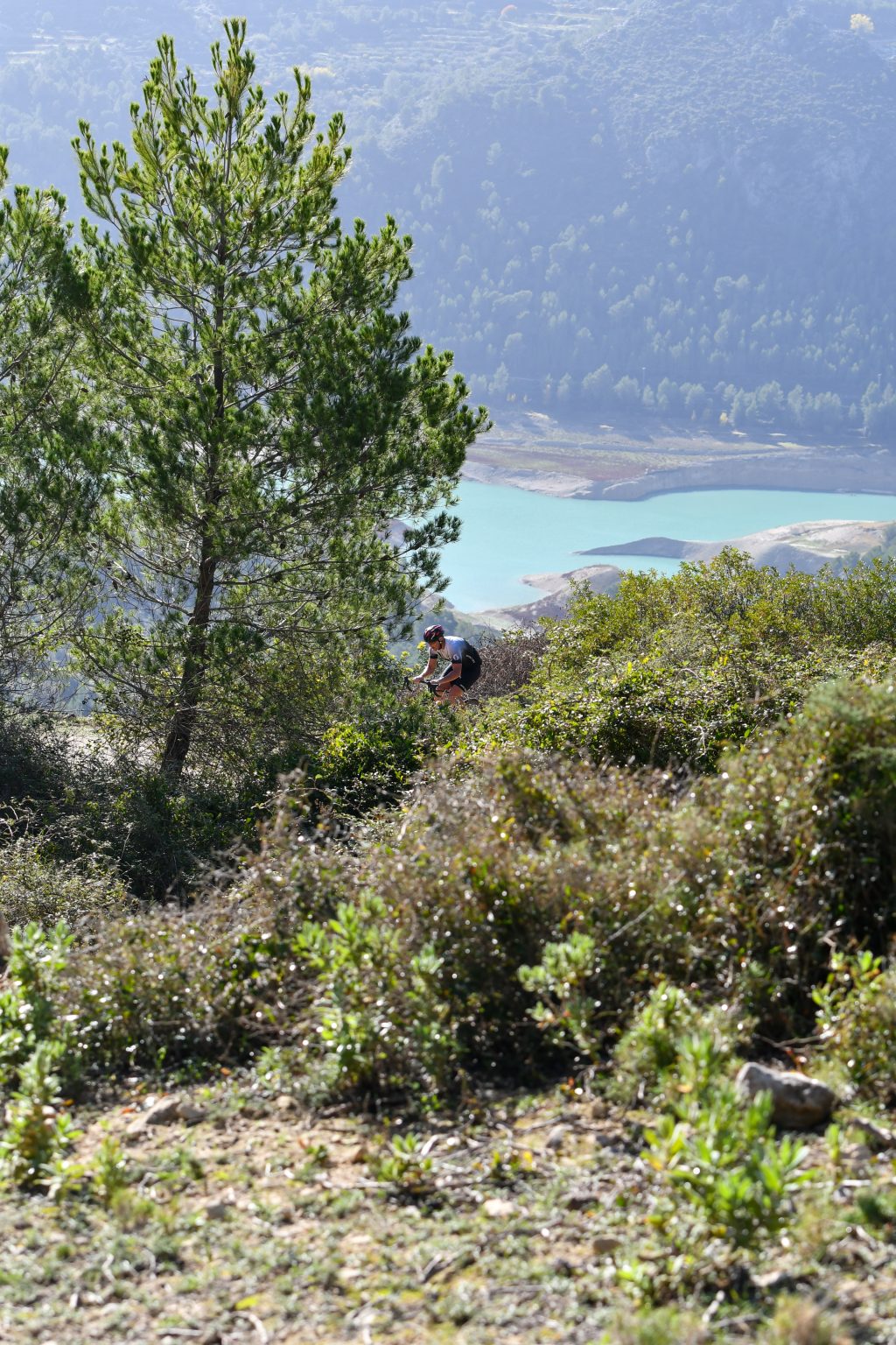 A road cyclist climbing above the turquoise Guadalest reservoir, Costa Blanca